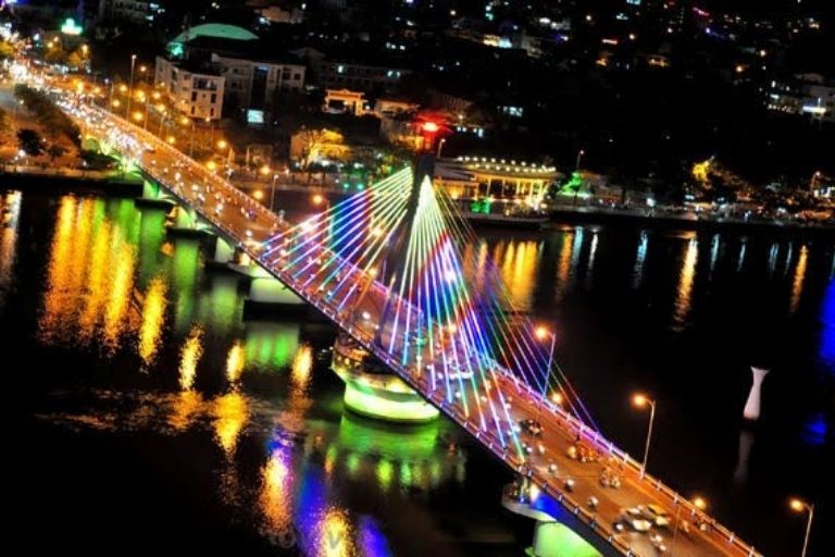Cầu sông Hàn về đêm khi đang quay, hai nhịp cầu tách ra giữa ánh đèn rực rỡ và dòng sông lấp lánh bên dưới.
