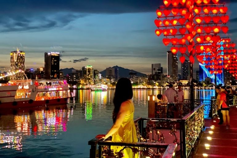 Cầu Tình Yêu Đà Nẵng vào ban đêm với những chiếc đèn hình trái tim đỏ rực và hàng loạt ổ khóa tình yêu treo dọc lan can.