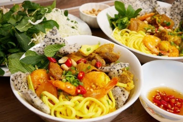 Tô Mì Quảng nóng hổi với sợi mì vàng, nhân tôm thịt, trứng cút, đậu phộng và rau sống tươi.