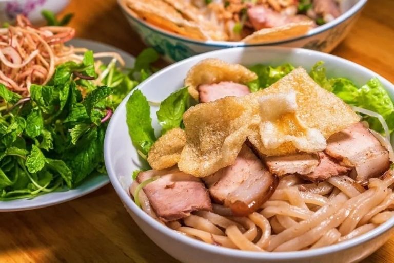 Món Cao Lầu Hội An với sợi mì đặc trưng, thịt xá xíu, da heo chiên giòn, rau sống và nước sốt sền sệt.